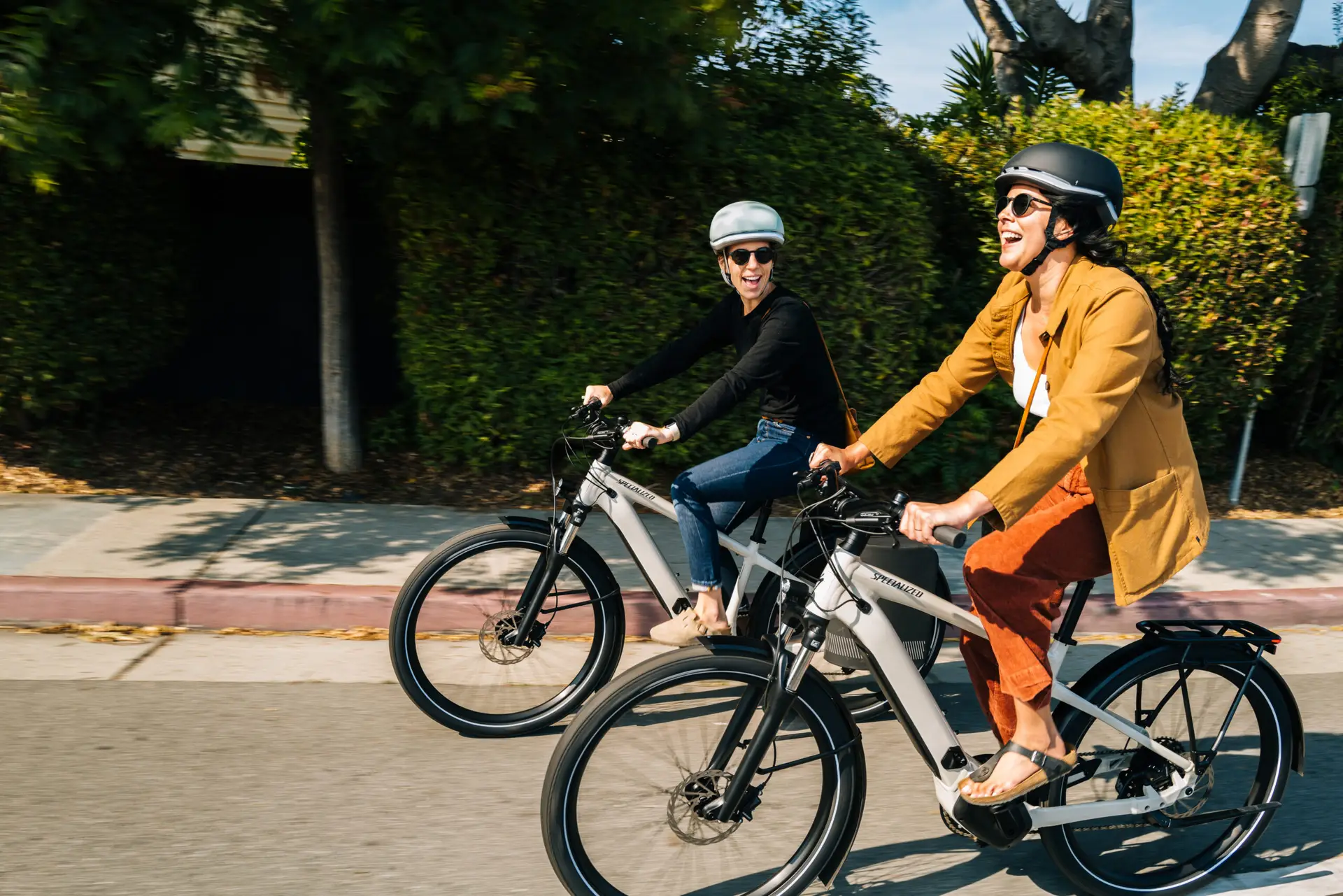 Twee vrouwen rijden lachend naast elkaar op e-bikes
