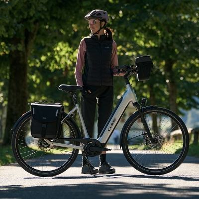 Een vrouw staat naast haar e-bike met fietstassen