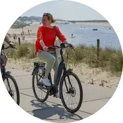 Vrouw fietst op een Gazelle Grenoble langs het strand